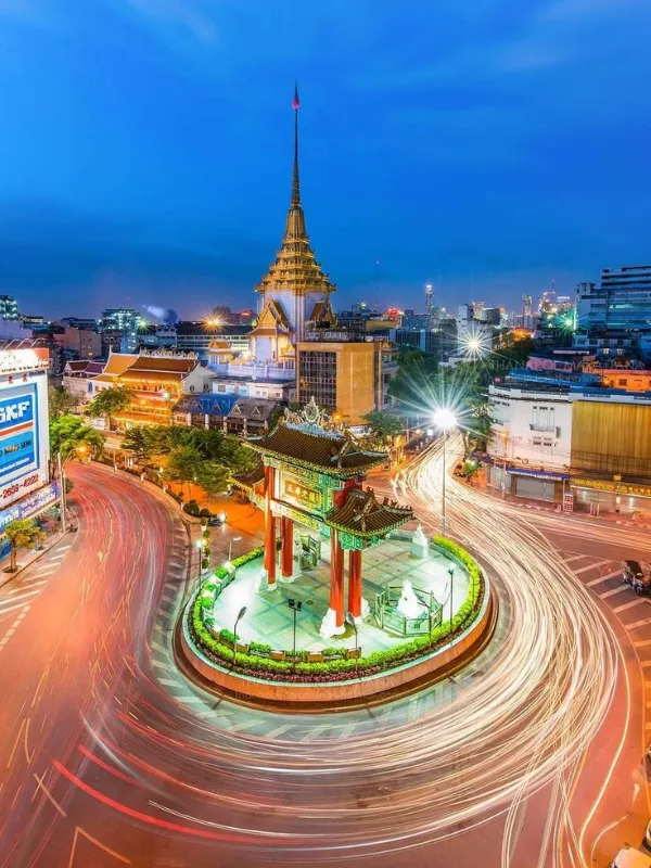 Visitantes fotografam portão vermelho iluminado na Yaowarat