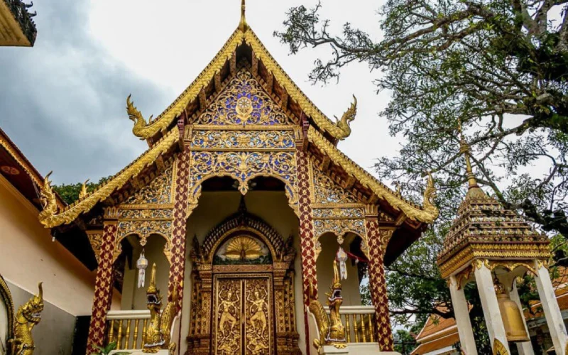 Estupa dourada brilhante cercada por estátuas e detalhes sagrados em Chiang Mai