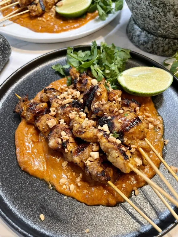 Tailandeses grelham espetos e servem com amendoim